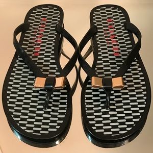 COACH black flip flops with gold bow.
